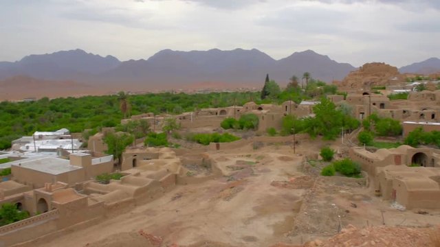 old adobe village located in an oasis at sunset, around a deserted place, in the distance a long ridge