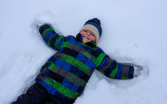 boy lying in the snow and waving arms and legs