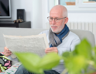 handsome mature man reading newpaper on sofa