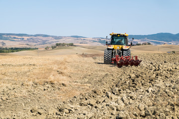 Obraz premium Peasant on the tractor while preparing the field for sowing