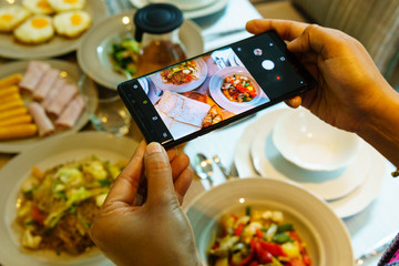 close up woman hand taking photo of foods with smart phone in the morning.