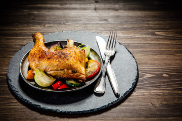 Barbecued chicken leg with baked potatoes and vegetables