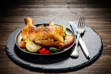 Barbecued chicken leg with baked potatoes and vegetables