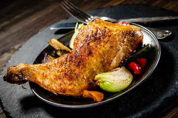 Barbecued chicken leg with baked potatoes and vegetables