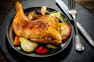 Barbecued chicken leg with baked potatoes and vegetables