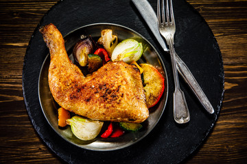 Barbecued chicken leg with baked potatoes and vegetables