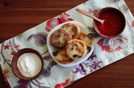 Homemade cottage cheese pancakes sour cream raspberry jam in clay cup on linen napkin