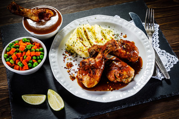 Grilled chicken legs with boiled potatoes on wooden background