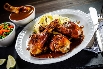 Grilled chicken legs with boiled potatoes on wooden background