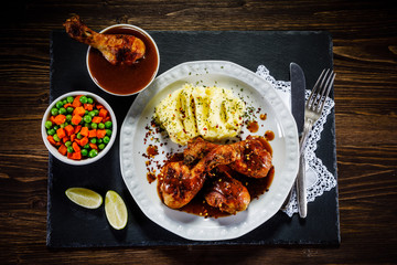 Grilled chicken legs with boiled potatoes on wooden background