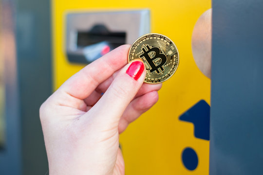 Woman pay with gold bitcoin at the vending machine. Close up.