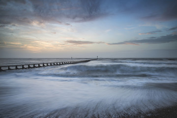 Obraz premium Beautiful dramatic stormy landscape image of waves crashing onto beach at sunrise