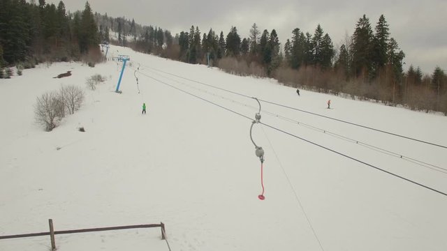 Ski lift carrying skier up to the snowy mountain. Drone shot. 4K