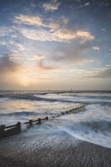 Beautiful dramatic stormy landscape image of waves crashing onto beach at sunrise