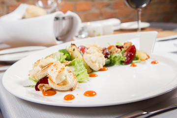 Starter: Mix salads, baked goat cheese, sea-buckthorn jam, caramelized pear with thyme, plum and roast nuts - served in a restaurant