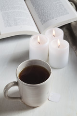 Mug of tea with candles book and cozy blanket