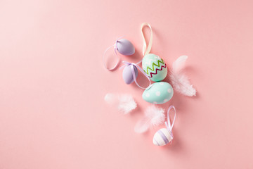 Easter Eggs and feathers on pastel pink background