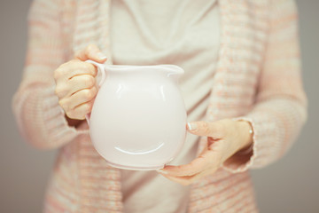 beautiful woman hands holding vintage antique milk pot, sensual atmospheric studio shot in rose, pink