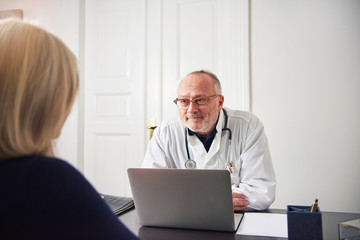 Woman in hospital talking with therapist sitting at laptop