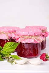 Preserved berry. Glass jar with homemade raspberry jam on a white background.