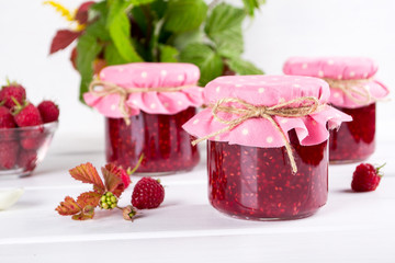 Preserved berry. Glass jar with homemade raspberry jam on a white background.
