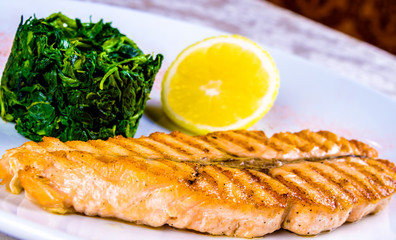 Grilled salmon steak with stewed spinach on white plate