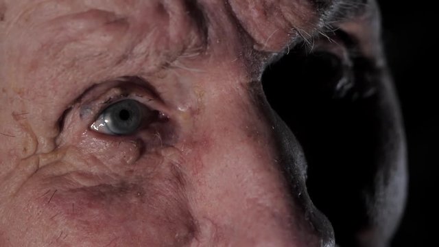 Very old 92 years man portrait. Grandfather sad and depressed. Aged, elderly, loneliness, senior. Macro eyes of man sitting alone. Slow motion.