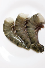 Fresh, raw, uncooked headless tiger prawns. Sea shrimps on white background.
