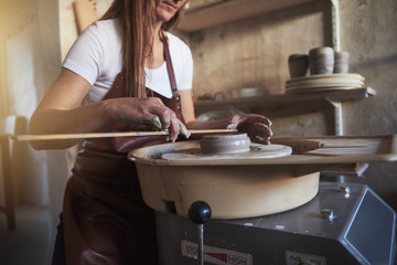 Creative artisan measuring a turning vase in her workshop