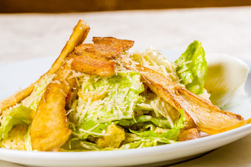 Caesar salad with chicken and parmesan cheese on white plate