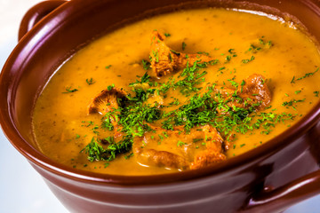 Cream soup with chanterelles, potato and herbs in ceramic pot