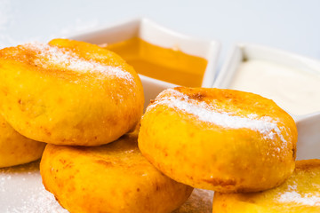 Cottage cheese pancakes with honey and sour cream on white plate