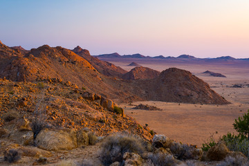 Rocky desert at dusk, colorful sunset over the Namib desert, Namibia, Africa, glowing rocks and canyon. - obrazy, fototapety, plakaty
