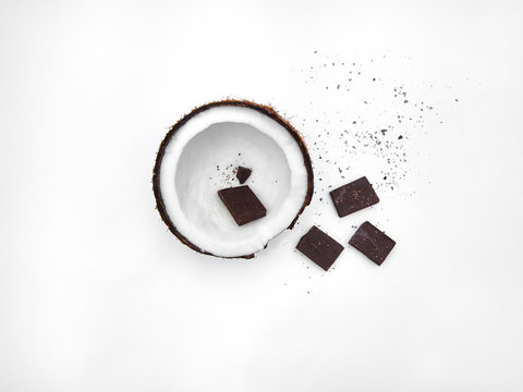 Coconut Flat lay Half coconut in peel and broken chocolate bars are lying on white background Top view Trendy colorful photo mockup with space for text