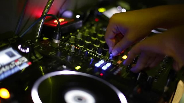 Dj hands playing and mixing music in a nightclub
