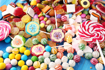 Fototapeta na wymiar candies with jelly and sugar. colorful array of different childs sweets and treats on light blue wood background