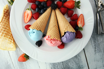 Set of ice cream scoops of different colors and flavours with blueberries, raspberries and blackberries.