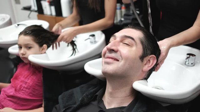 father and daughter in hair salon cleaning hair with shower