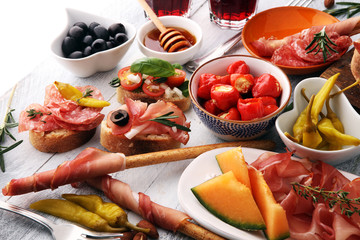 Italian antipasti wine snacks set. Cheese variety, Mediterranean olives, pickles, Prosciutto di Parma, tomatoes, artichokes and wine in glasses