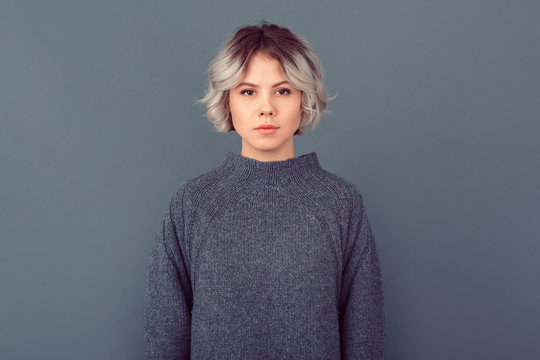 Young Woman In A Grey Sweater Studio Picture Isolated On Grey Background Serious