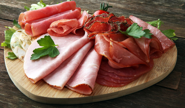 Food tray with delicious salami, pieces of sliced ham, sausage, tomatoes, salad and vegetable - Meat platter with selection