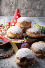 German donuts with jam and icing sugar. Carnival powdered sugar raised donuts with paper streamers.