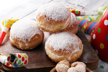 German donuts with jam and icing sugar. Carnival powdered sugar raised donuts with paper streamers.