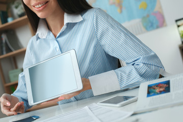 Young female travel agent consultant in tour agency showing online service