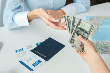 Young female travel agent consultant in tour agency with a customer cash payment close-up