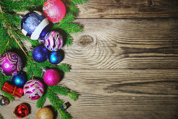 Christmas balls lie on fir branches on a wooden background