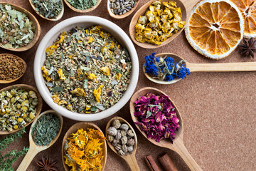 Mix of dried herbs on wooden spoons with copy space, top view