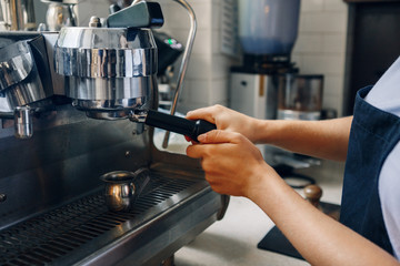 Closeup of  barista making coffee using coffee machine. Small local business with organic hot drinks products.