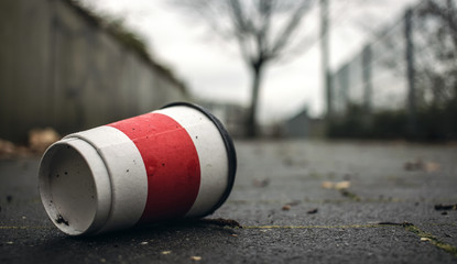 Weggeworfener leerer Kaffeebecher liegt auf Gehweg.