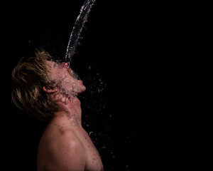 shirtless blond caucasian man getting hit in face by stream of water